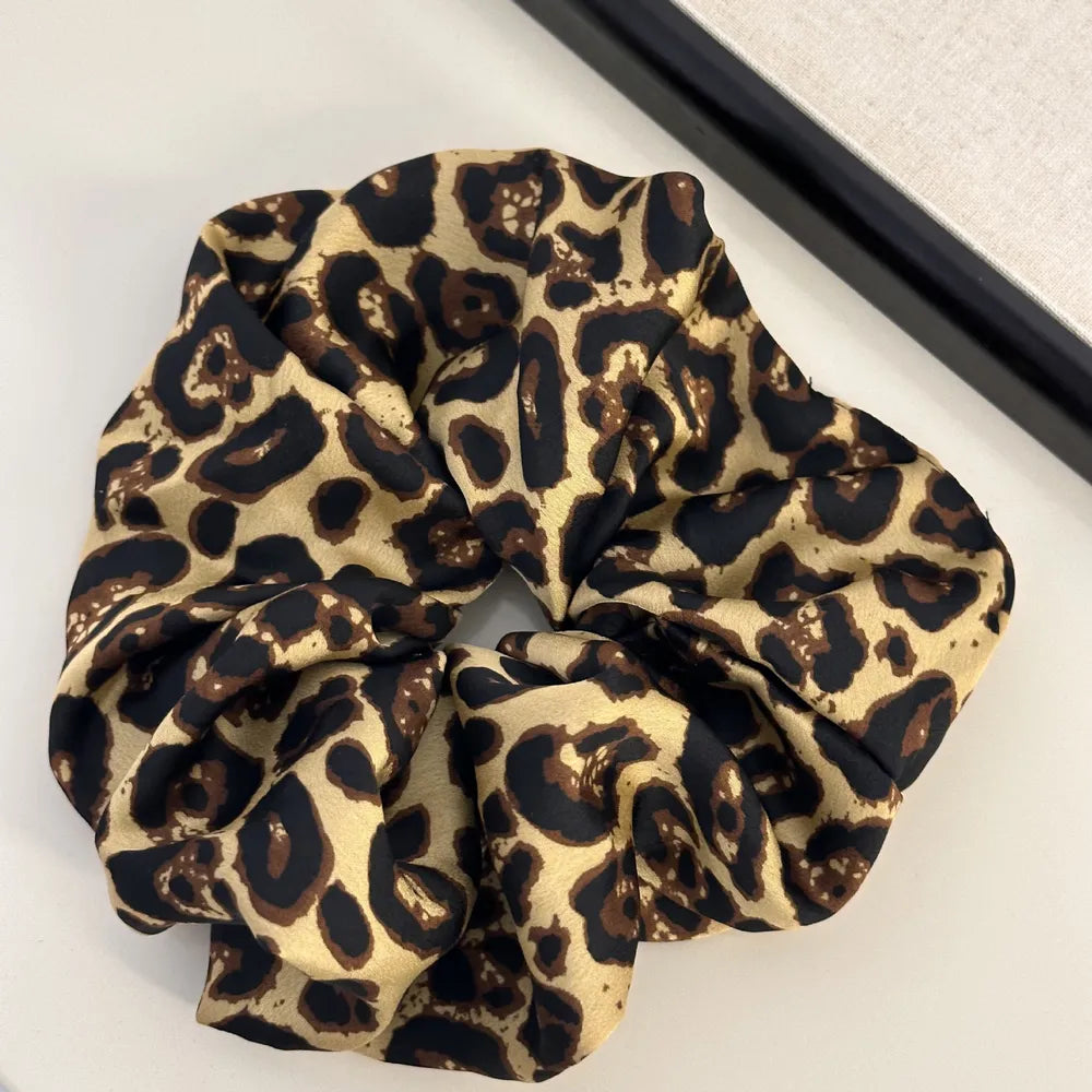 Tan and black leopard print oversized scrunchie flat lay showing warm golden base with dark brown and black spots