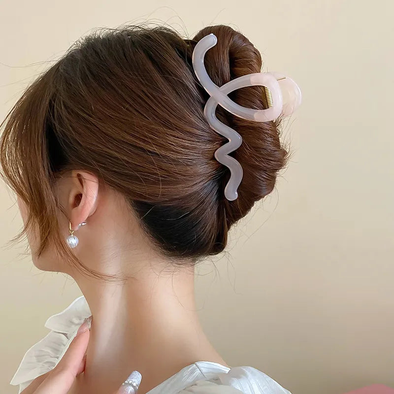 Person with a hair clip in their bun against a beige background